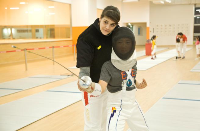 万国体育_老师指导孩子击剑动作